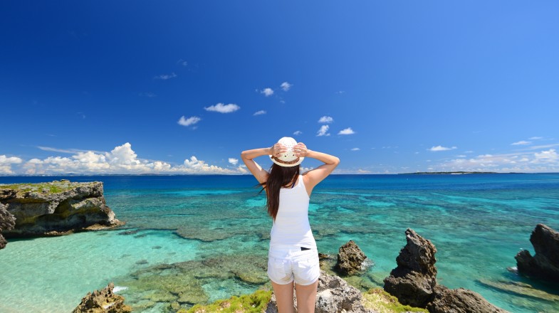 A woman admiring the beauty of Okinawa beach during summer in Japan.